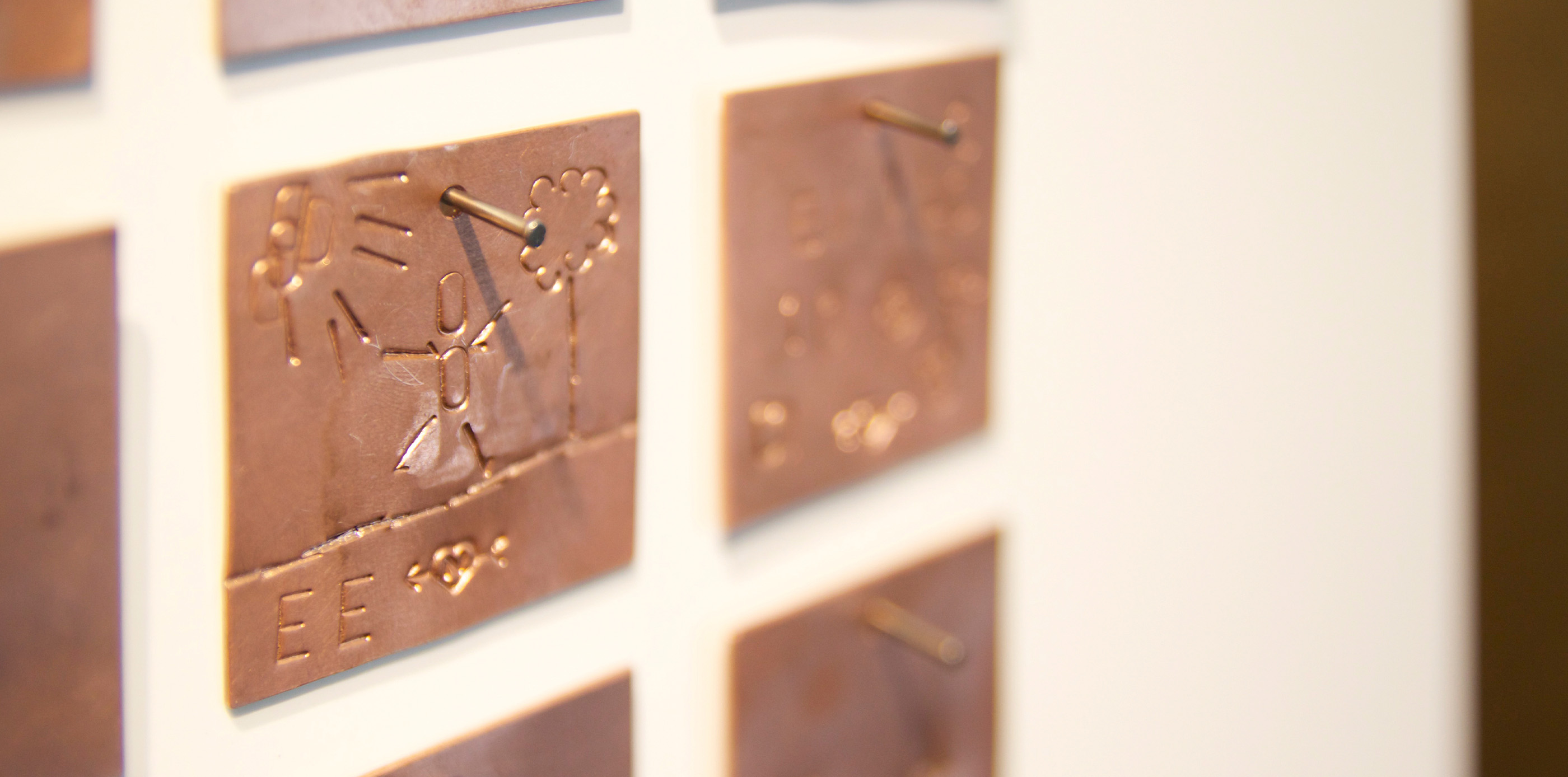 Kleine Goldplatten mit einem Nagel an der Wand befestigt